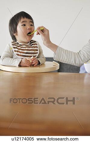 Stock Photography - Mother feeding baby boy. Fotosearch
