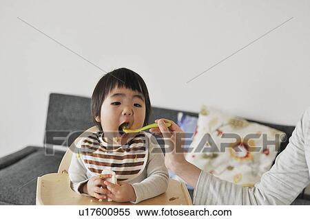 Stock Photography - Mother feeding baby boy. Fotosearch