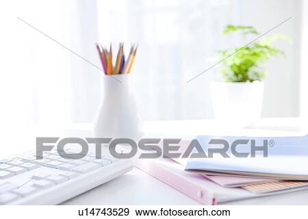 Stock Photo - Notebooks and colored pencils on desk in office. Fotosearch