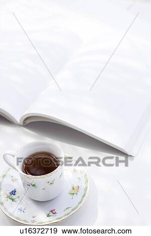 Stock Photo - Opened book and cup of tea, white background. Fotosearch