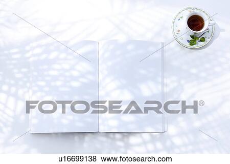 Stock Photo - Opened book and cup of tea, white background. Fotosearch