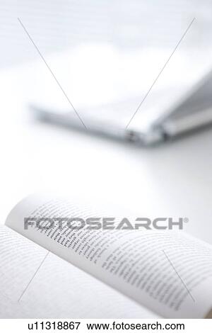 Stock Photo - Opened book and laptop on desk, close up, differential focus. Fotosearch