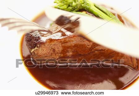 Stock Image - Plate of braised beef, close up, white background. Fotosearch