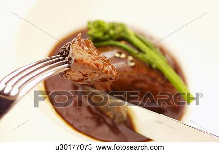 Stock Image - Plate of braised beef, close up, white background. Fotosearch