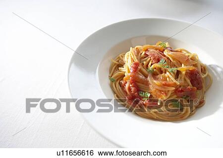 Stock Photograph - Plate of tomato spaghetti, white background. Fotosearch