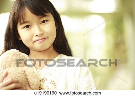 Stock Image - Portrait of a girl holding stuffed animal. Fotosearch