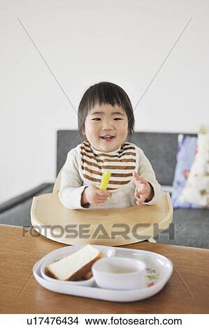 Picture - Portrait of baby boy sitting in high chair, smiling. Fotosearch