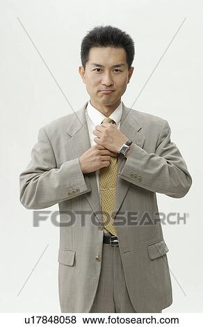 Portrait of businessman adjusting tie, white background View Large Photo Image Stock Photo - Portrait of businessman adjusting tie, white background. Fotosearch