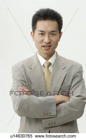 Stock Photography - Portrait of businessman with arms crossed, smiling, white background. Fotosearch