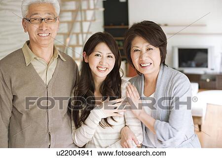 Stock Image - Portrait of family in living room, smiling. Fotosearch