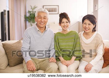 Stock Image - Portrait of family sitting on sofa, smiling. Fotosearch
