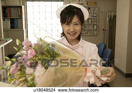 Picture - Portrait of female nurse holding flower bouquet, smiling. Fotosearch