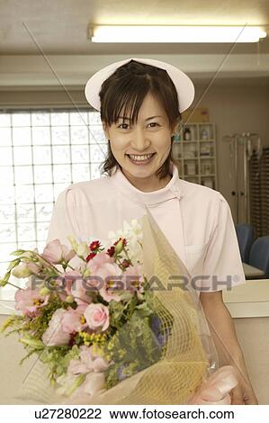 Portrait of female nurse holding flower bouquet, smiling View Large Photo Image Stock Image - Portrait of female nurse holding flower bouquet, smiling. Fotosearch