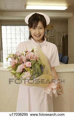 Portrait of female nurse holding flower bouquet, smiling View Large Photo Image Stock Photography - Portrait of female nurse holding flower bouquet, smiling. Fotosearch