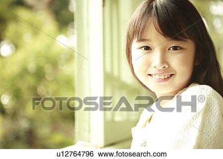 Stock Photograph - Portrait of girl by window, close up, differential focus, Kobe city, Hyogo prefecture, Japan. Fotosearch