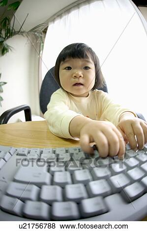 Stock Photo - Portrait of girl touching computer keyboard, fish-eye lens. Fotosearch