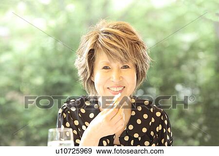 Stock Photo - Portrait of mature woman at cafe, smiling, differential focus. Fotosearch