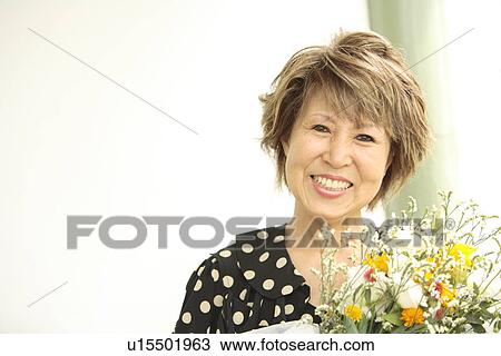 Portrait of mature woman holding flower bouquet, smiling View Large Photo Image Stock Image - Portrait of mature woman holding flower bouquet, smiling. Fotosearch