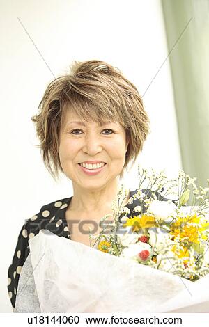 Portrait of mature woman holding flower bouquet, smiling View Large Photo Image Stock Image - Portrait of mature woman holding flower bouquet, smiling. Fotosearch