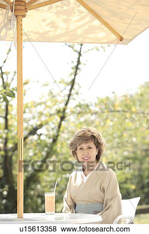 Stock Photo - Portrait of mature woman in Kimono sitting at cafe table, Kyoto city, Kyoto prefecture, Japan. Fotosearch