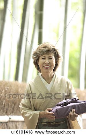 Stock Photo - Portrait of mature woman in Kimono holding gift, Kyoto city, Kyoto prefecture, Japan. Fotosearch