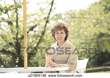 Stock Photograph - Portrait of mature woman in Kimono sitting at cafe table, Kyoto city, Kyoto prefecture, Japan. Fotosearch