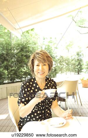 Portrait of mature woman sitting at table in cafe, smiling View Large Photo Image Stock Image - Portrait of mature woman sitting at table in cafe, smiling. Fotosearch
