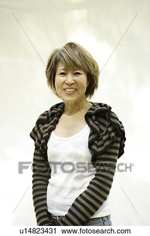 Stock Image - Portrait of mature woman smiling, white background. Fotosearch