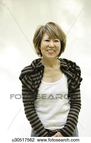 Stock Image - Portrait of mature woman smiling, white background. Fotosearch