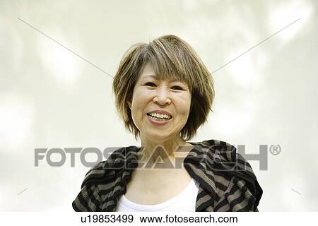 Stock Photo - Portrait of mature woman smiling, white background. Fotosearch