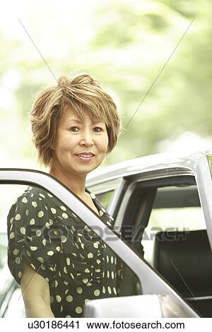 Portrait of mature woman standing by car, smiling View Large Photo Image Stock Image - Portrait of mature woman standing by car, smiling. Fotosearch