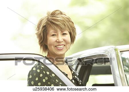 Portrait of mature woman standing by car, smiling View Large Photo Image Stock Photograph - Portrait of mature woman standing by car, smiling. Fotosearch