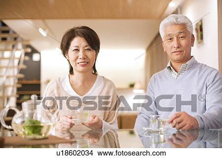 Picture - Portrait of senior couple drinking tea at dining table, smiling. Fotosearch