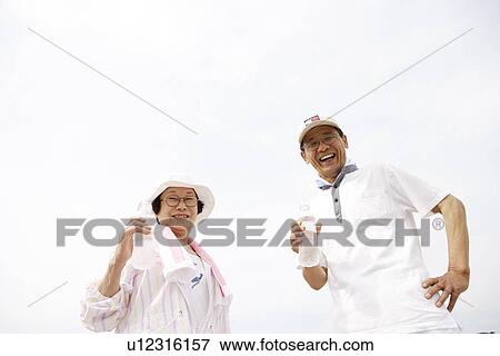Stock Photo - Portrait of senior couple holding bottles of water, smiling. Fotosearch