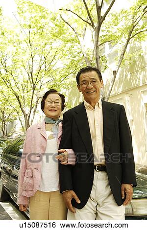 Stock Photograph - Portrait of senior couple standing arm in arm, smiling. Fotosearch
