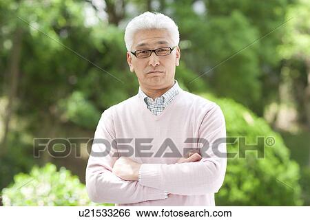 Stock Photograph - Portrait of senior man with arms crossed, looking at camera. Fotosearch