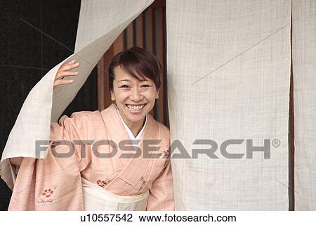 Stock Image - Portrait of woman in Kimono standing in Japanese restaurant entrance, Kyoto city, Kyoto prefecture, Japan. Fotosearch