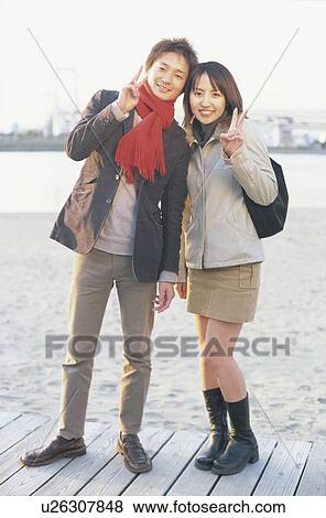 Portrait of young couple giving peace sign View Large Photo Image Stock Photo - Portrait of young couple giving peace sign. Fotosearch