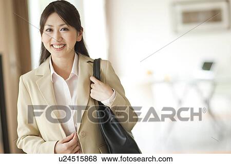 Stock Photo - Portrait of young woman holding bag on shoulder, smiling. Fotosearch