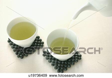Pouring green tea into a cups View Large Photo Image Stock Photo - Pouring green tea into a cups. Fotosearch