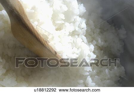 Stock Image - Rice and wooden spoon. Fotosearch