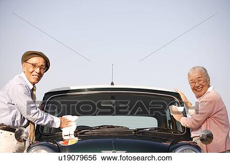 Stock Photograph - Senior couple cleaning windshield. Fotosearch
