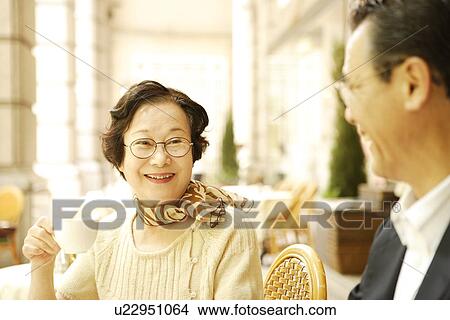 Senior couple sitting at table in cafe, smiling View Large Photo Image Picture - Senior couple sitting at table in cafe, smiling. Fotosearch