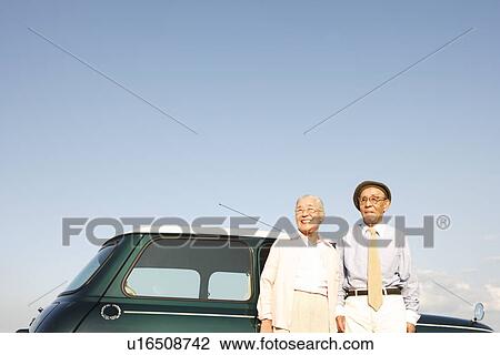 Senior couple standing in front of a car View Large Photo Image Stock Image - Senior couple standing in front of a car. Fotosearch