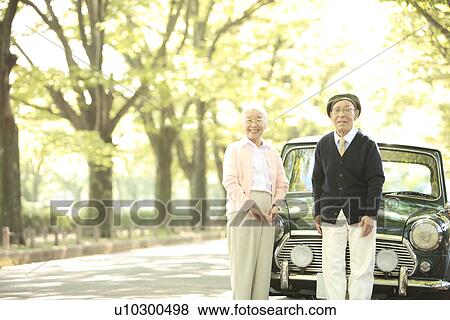 Stock Photo - Senior couple standing in front of a car. Fotosearch
