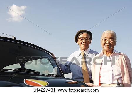 Senior couple standing next to a car View Large Photo Image Stock Image - Senior couple standing next to a car. Fotosearch