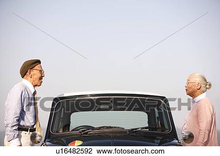 Senior couple standing next to a car View Large Photo Image Stock Image - Senior couple standing next to a car. Fotosearch