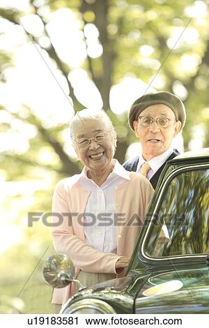 Senior couple standing next to a car View Large Photo Image Stock Image - Senior couple standing next to a car. Fotosearch