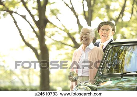 Senior couple standing next to a car View Large Photo Image Stock Image - Senior couple standing next to a car. Fotosearch