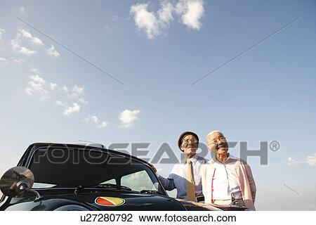 Stock Image - Senior couple standing next to a car. Fotosearch